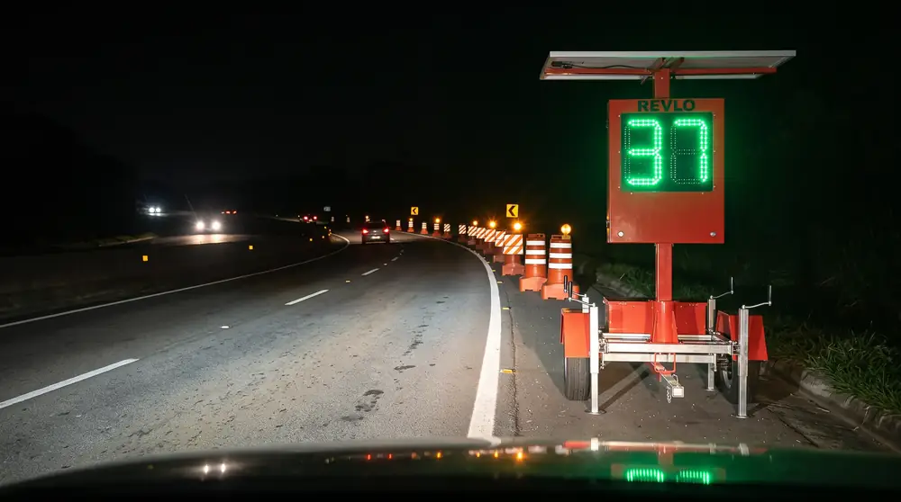 Lombada eletrônica móvel à noite antes de um desvio com cones na rodovia, mostrando 37